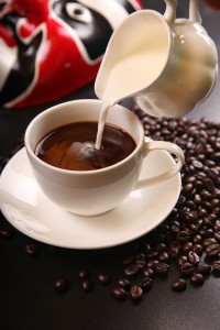 cup of coffee with milk being poured